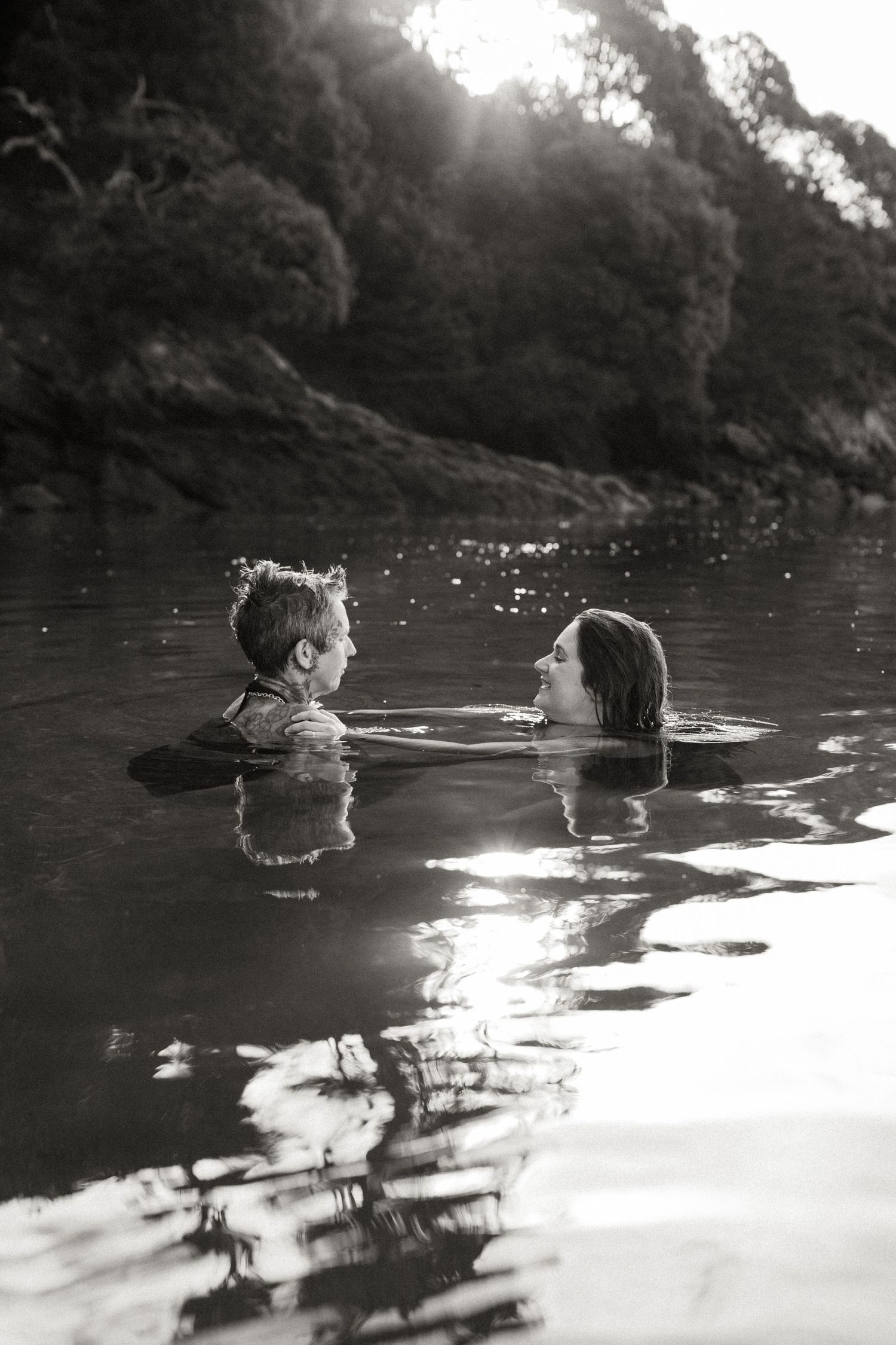 Two swimmers enjoying a calm lake during sunset in black and white.