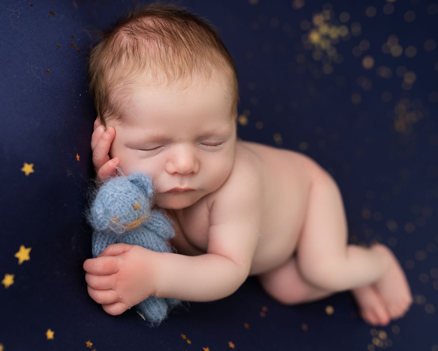baby boy layed on side with teddy on blue stary backdrop photographed by newborn photographer swansea