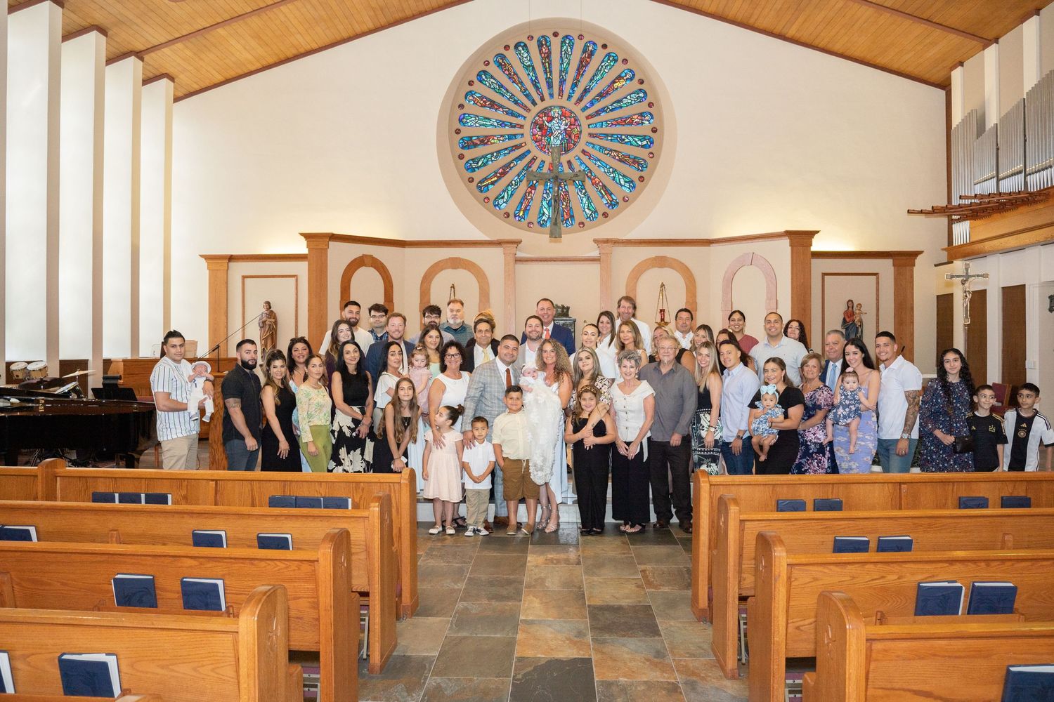 Church sanctuary with wooden ceiling and stained glass window during family gathering.