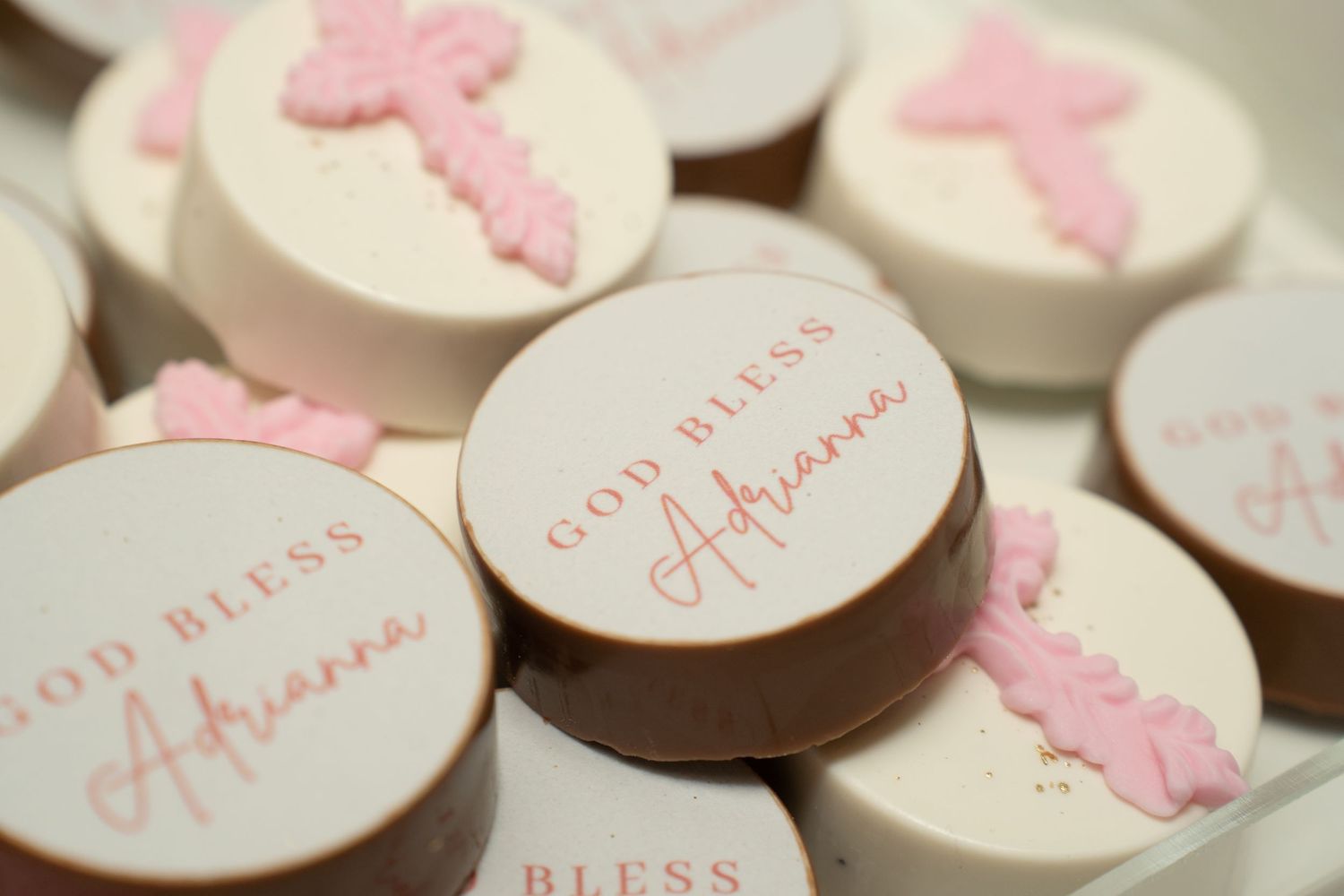 Pink and white decorated cupcakes and cookies arranged on a dessert table for a special occasion.