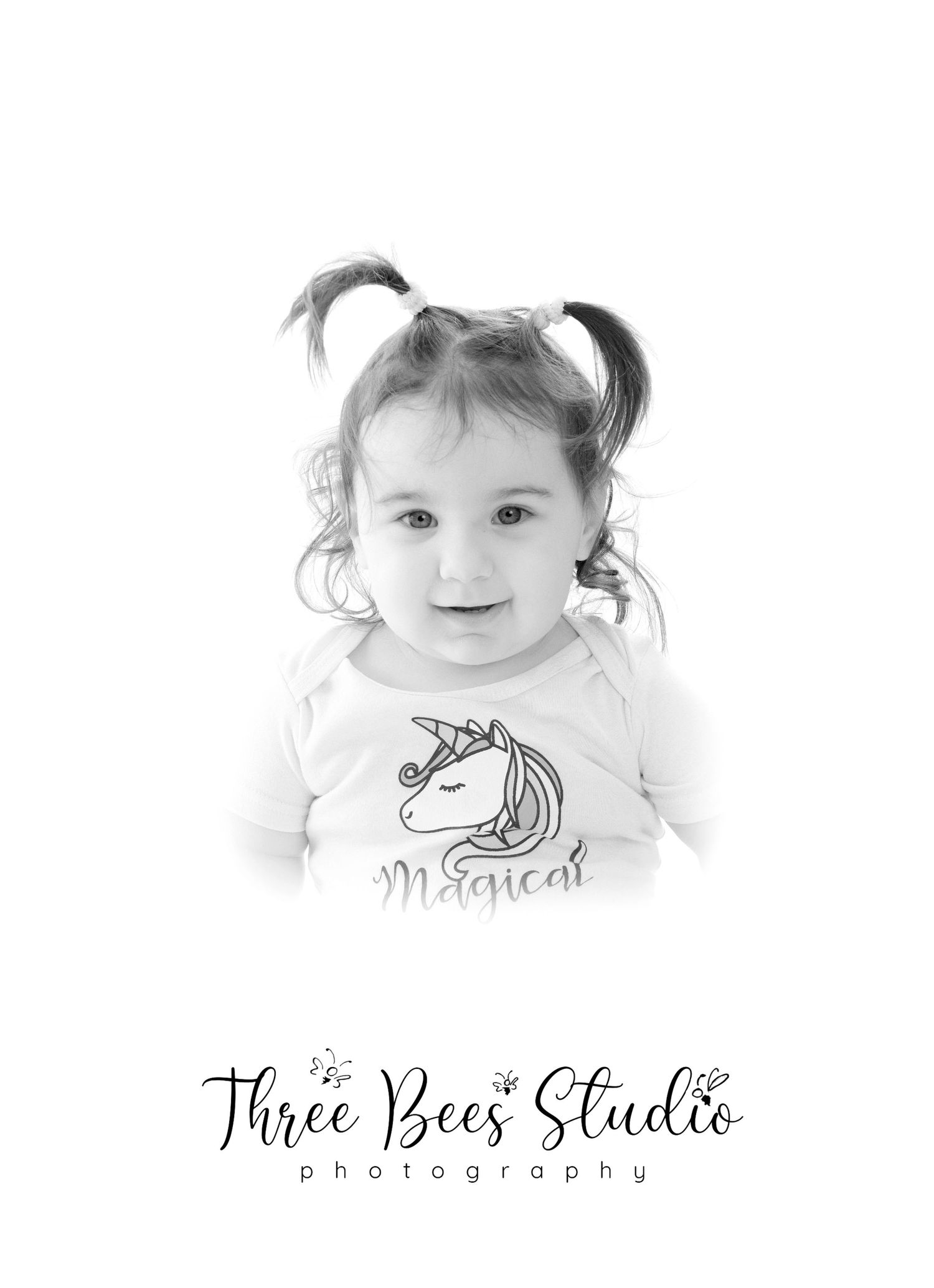 Black and white portrait of child wearing unicorn t-shirt with pigtails.