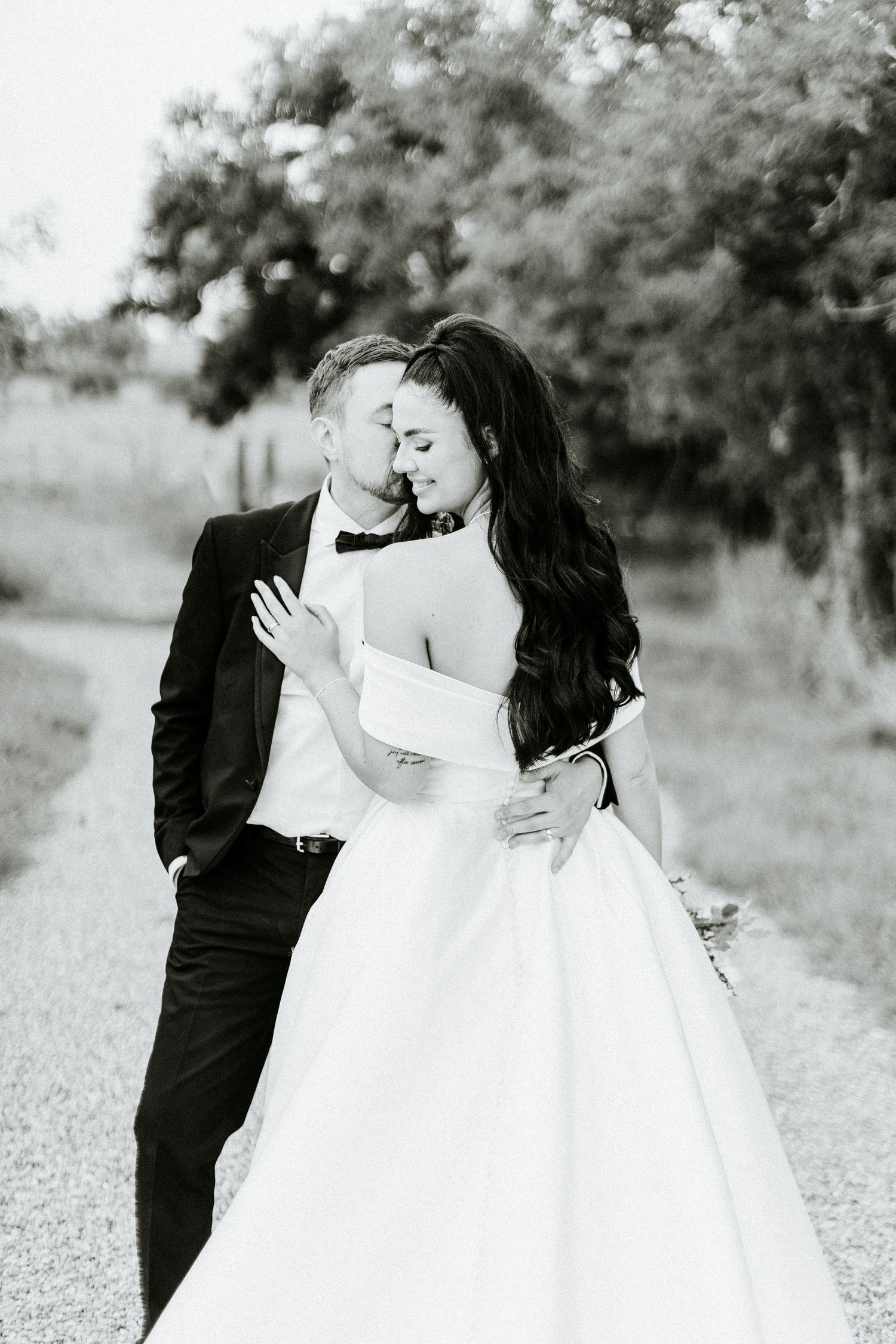 Black and white portrait of newlyweds sharing an intimate moment outdoors.