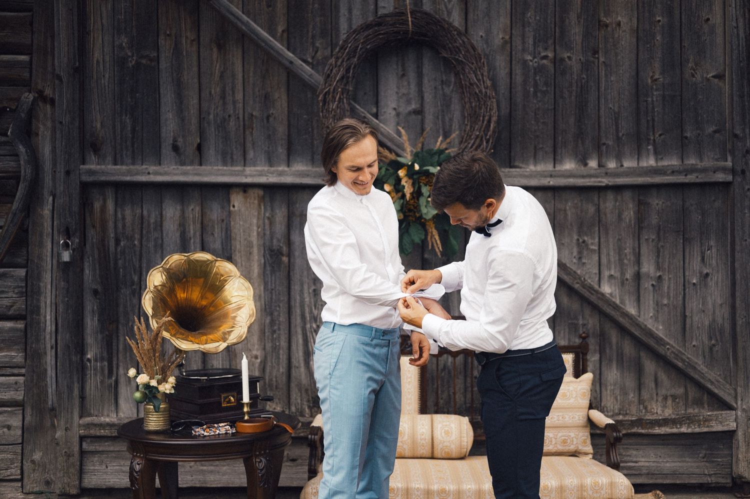 Two people in white shirts dancing near vintage gramophone against wooden wall.