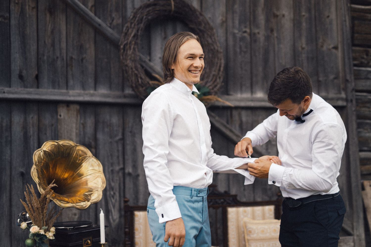 Two people sharing a lighthearted moment next to vintage gramophone against wooden backdrop.