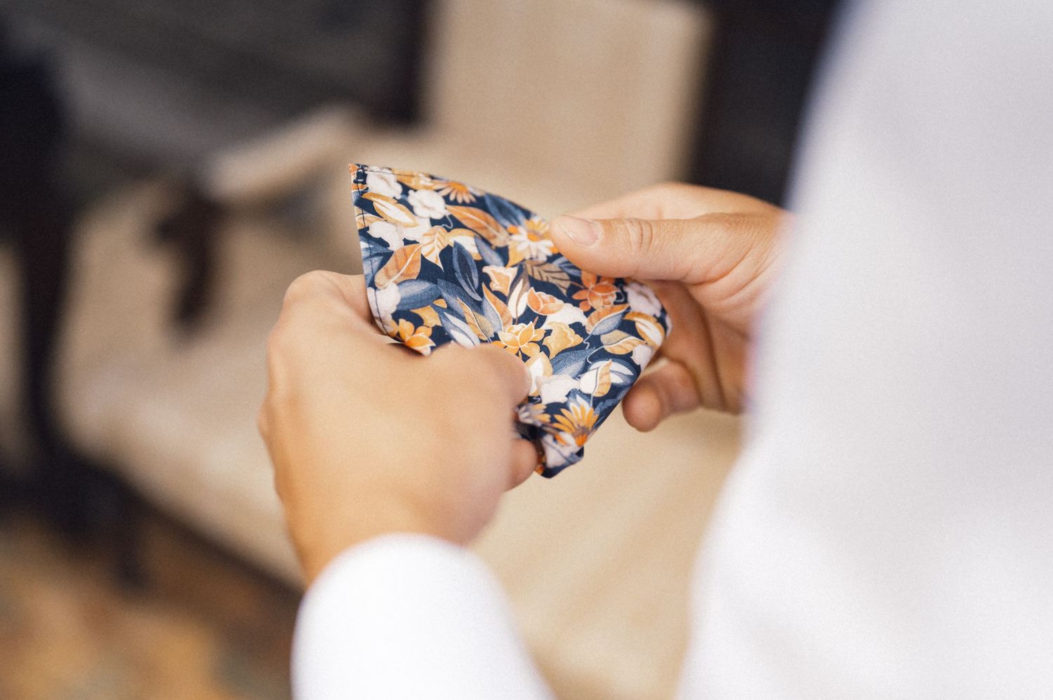 Hands holding a patterned blue and white bowtie in close-up view.