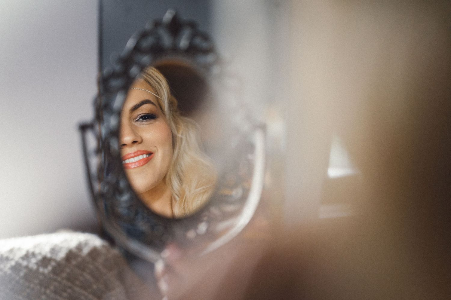 Artistic reflection in ornate mirror showing joyful wedding day preparation.