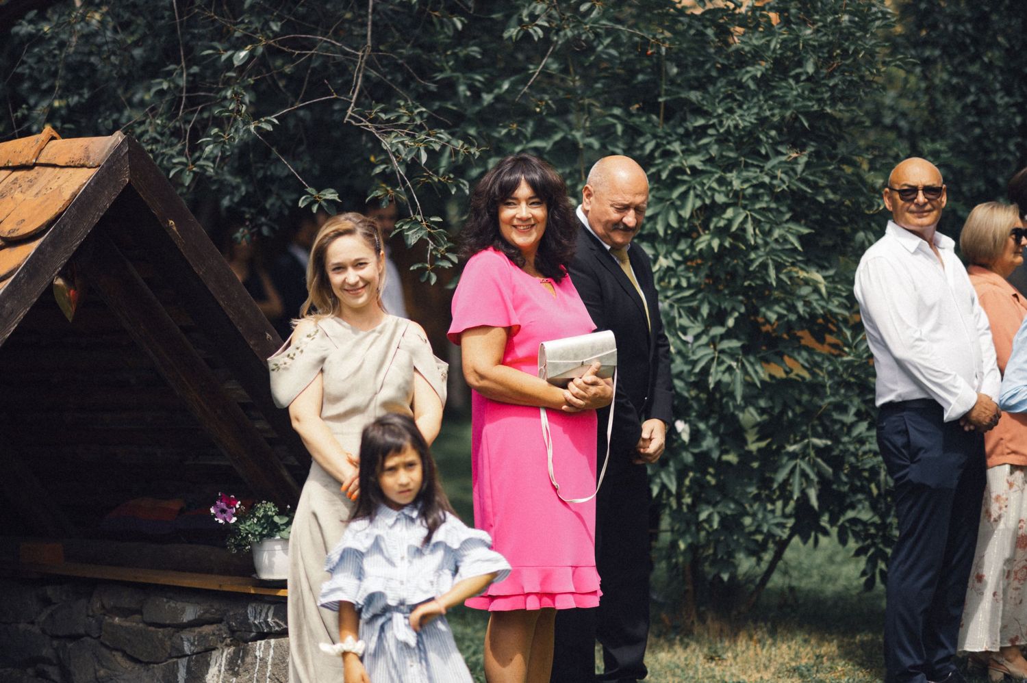 Wedding guests gathered near a wooden structure during an outdoor celebration.