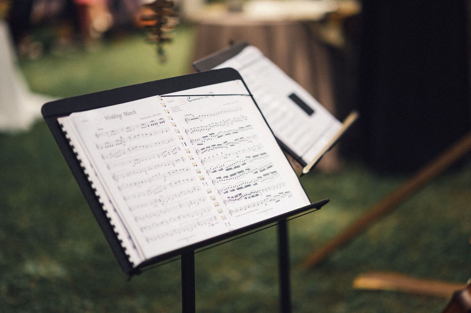 Sheet music displayed on a black metal music stand outdoors.