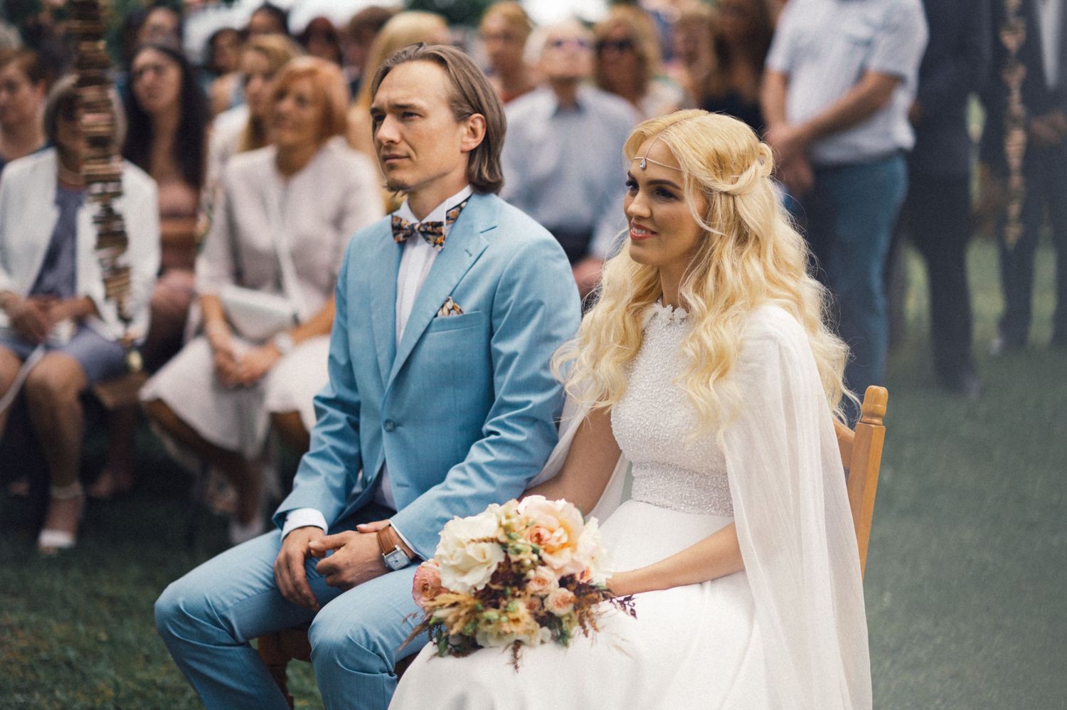 Outdoor wedding ceremony with couple seated beneath trees.