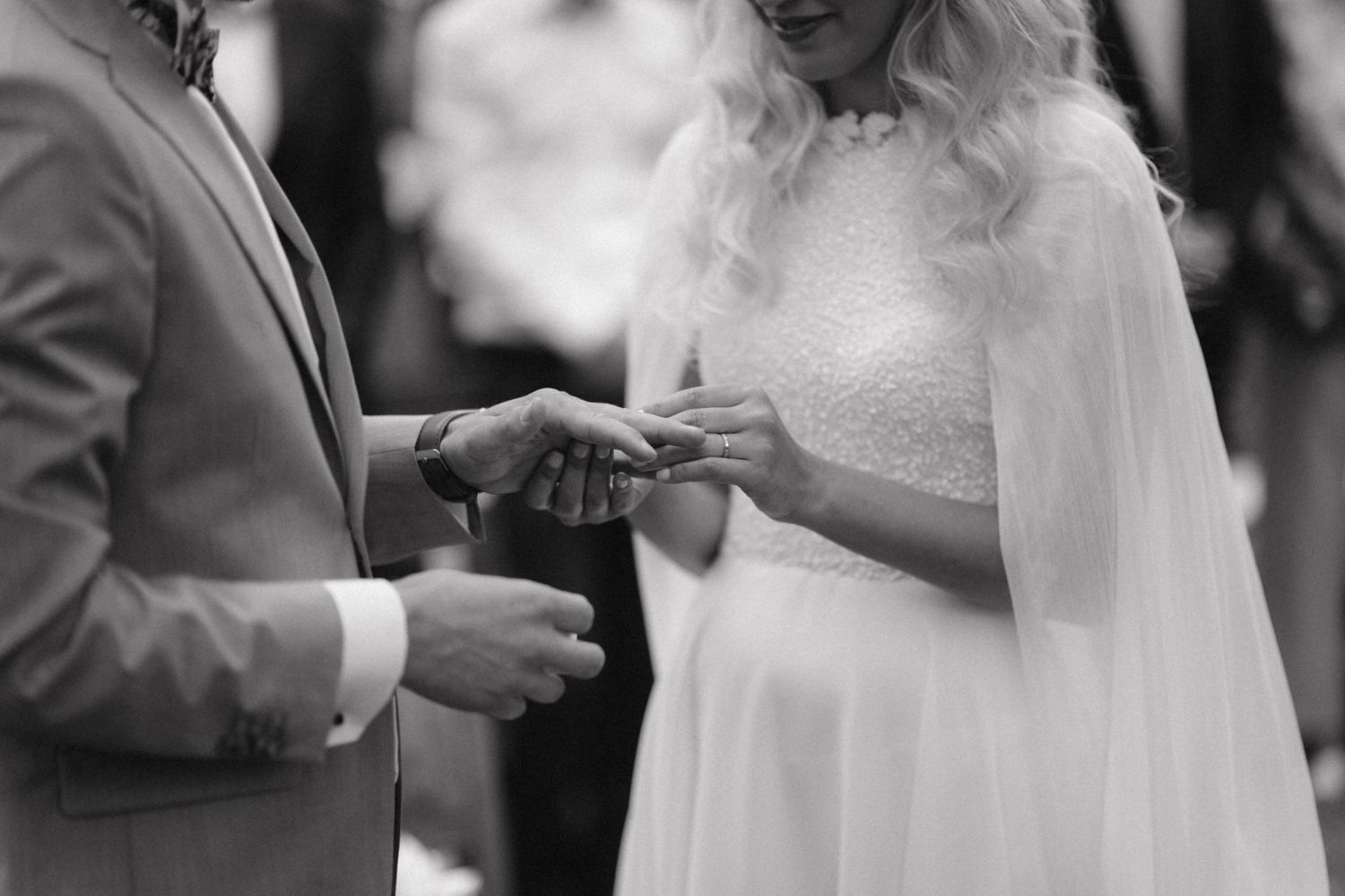 A black and white capture of a ring exchange during an intimate wedding ceremony.
