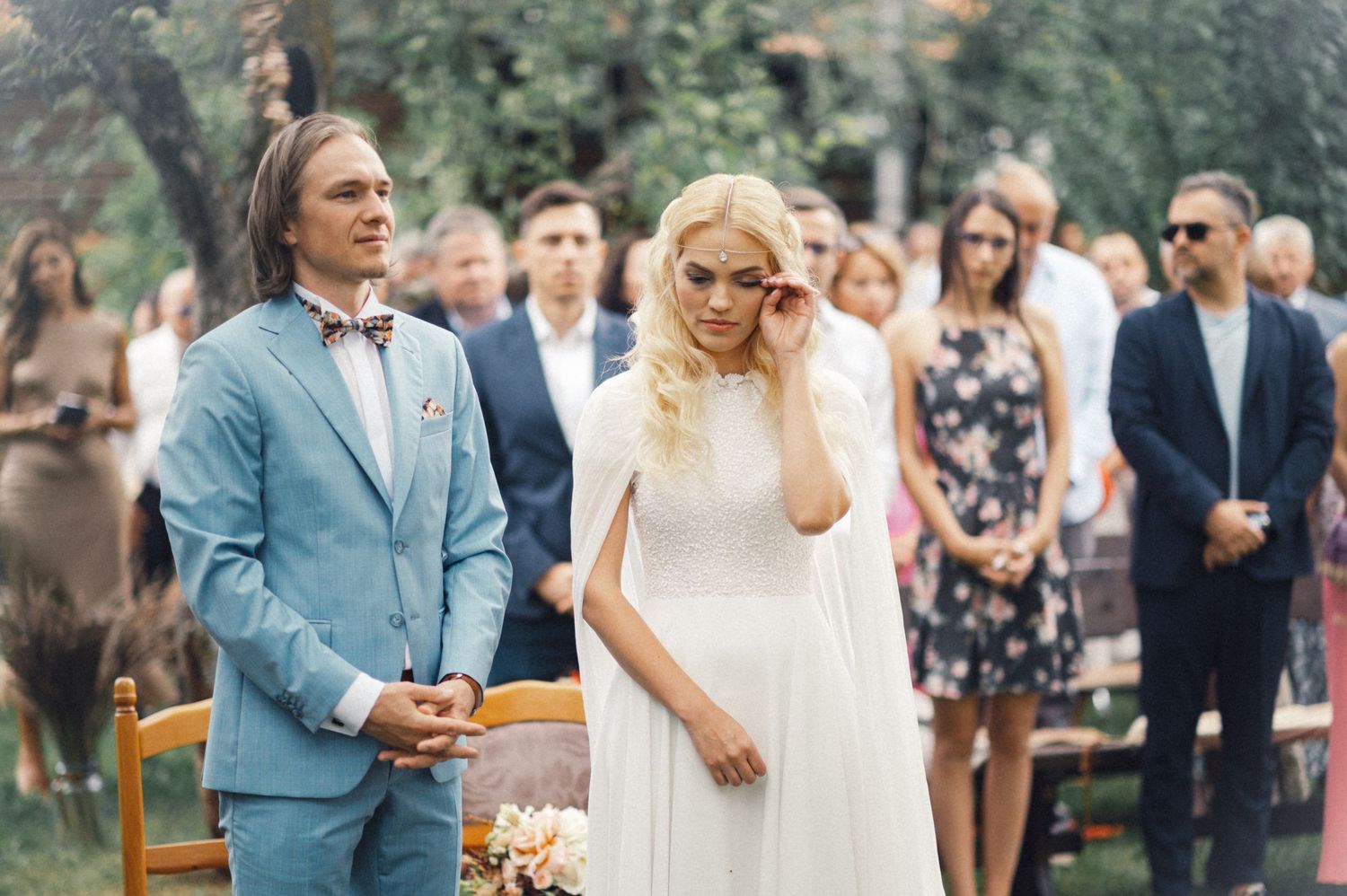 A couple stands together during their outdoor garden wedding ceremony.