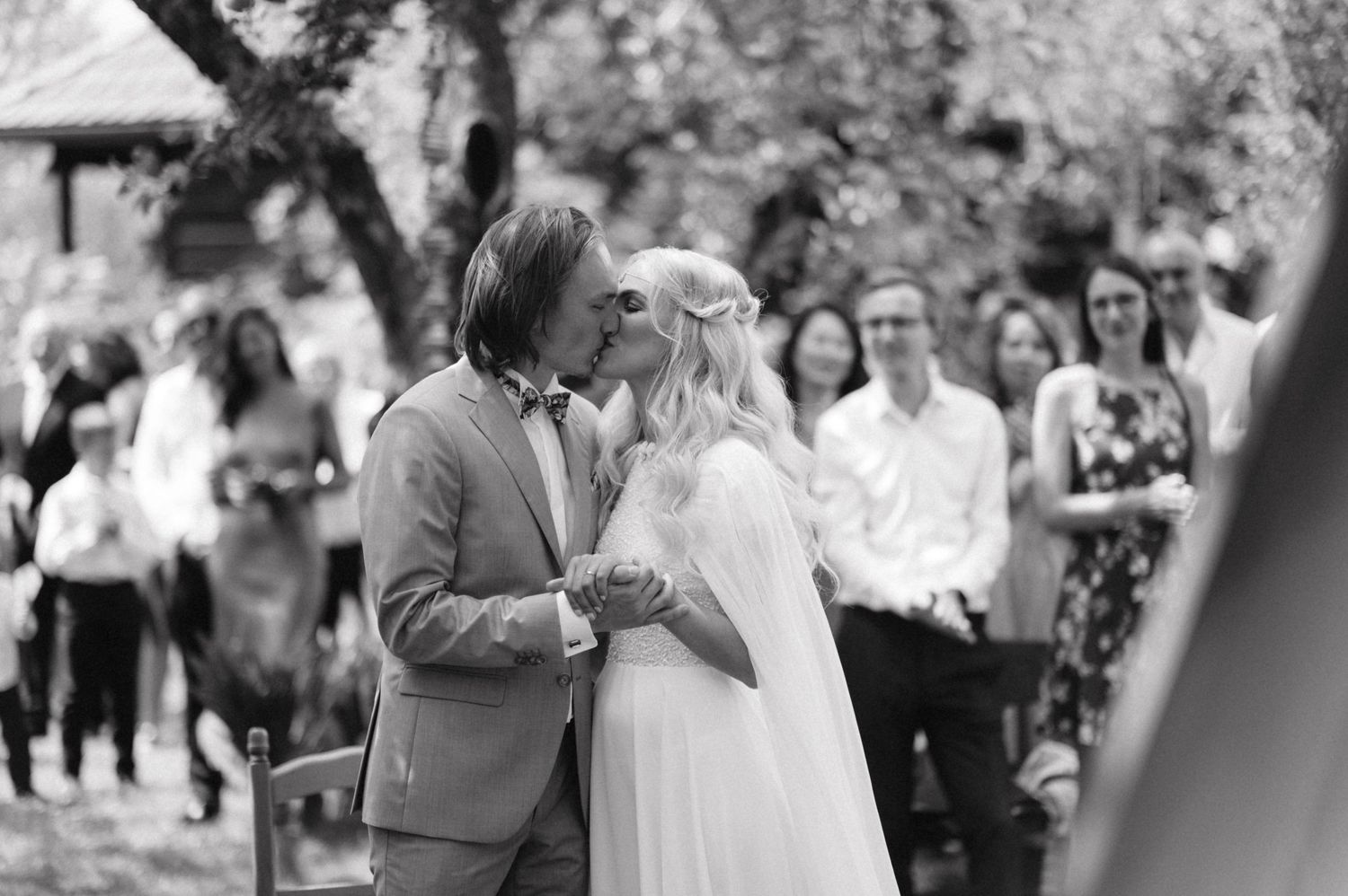 A black and white capture of a romantic moment during an outdoor wedding.