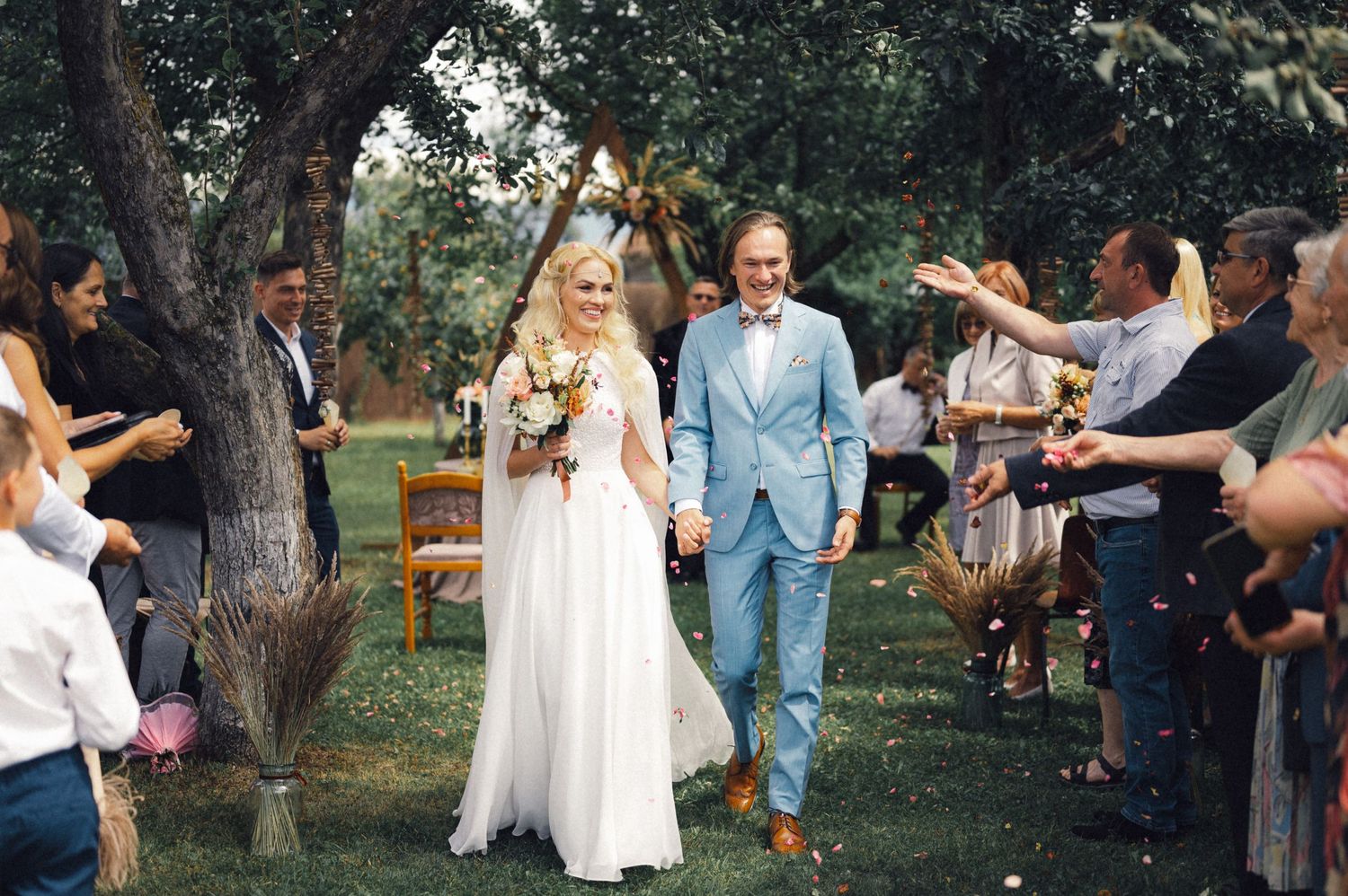 Newlyweds walk through a garden path lined with guests during their recessional.