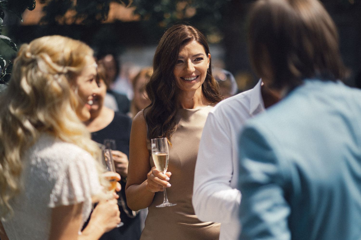 Wedding guests enjoying champagne and conversation at an outdoor garden reception.