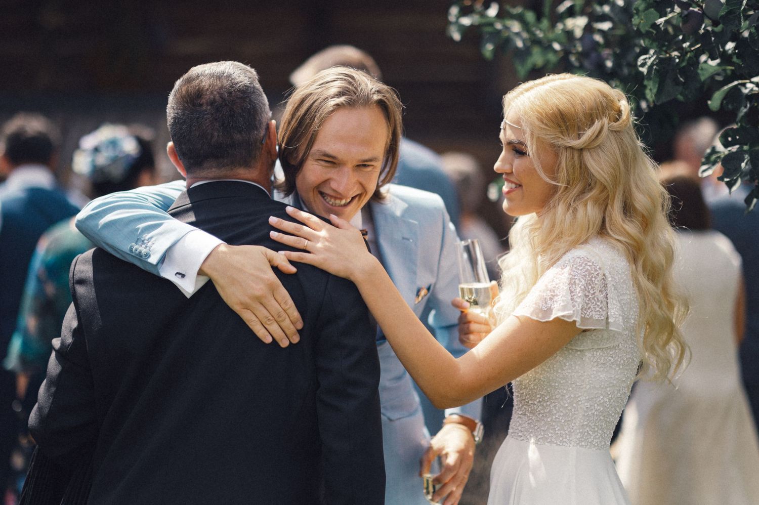 Guests share warm embraces during an outdoor wedding celebration.