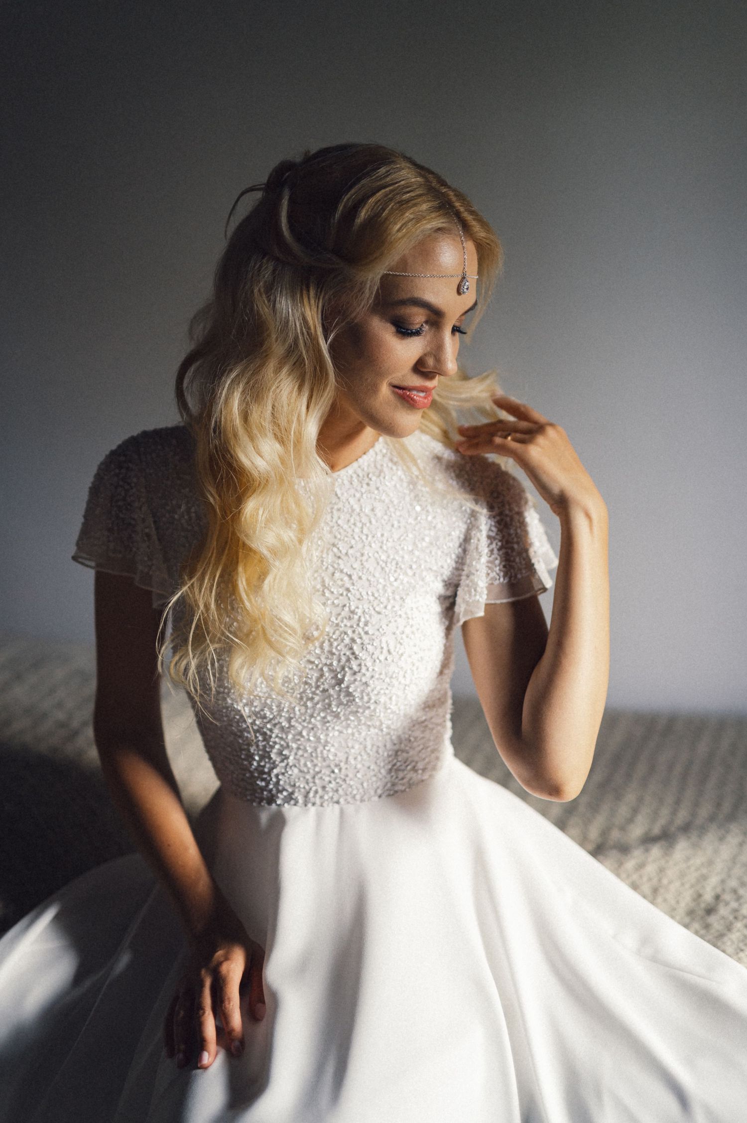 An elegant white lace wedding dress captured in soft, moody lighting.