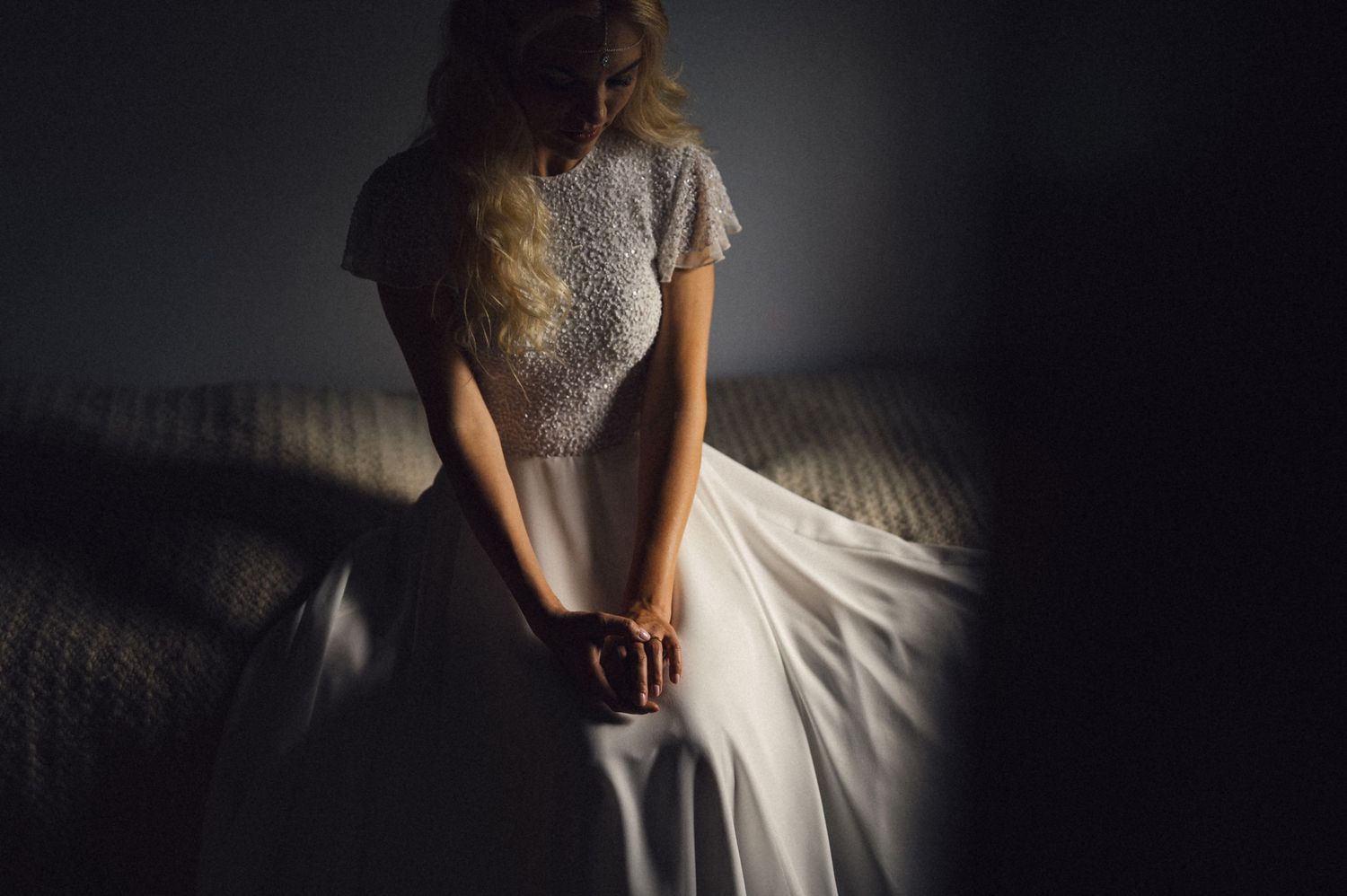 Artistic silhouette of a wedding dress with detailed lace bodice in dramatic lighting.