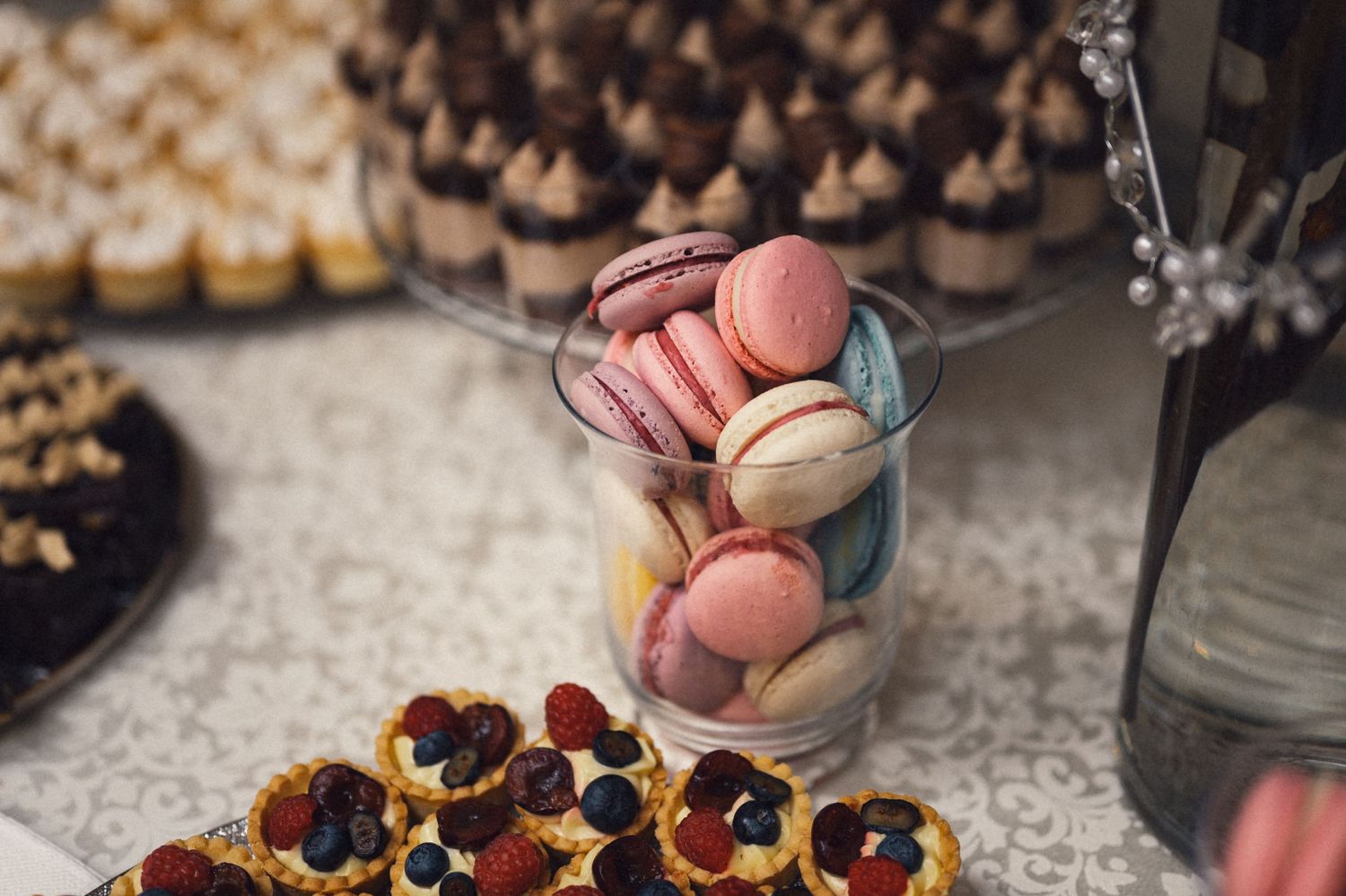 Colorful macarons and mini desserts displayed on a dessert table at a wedding reception.