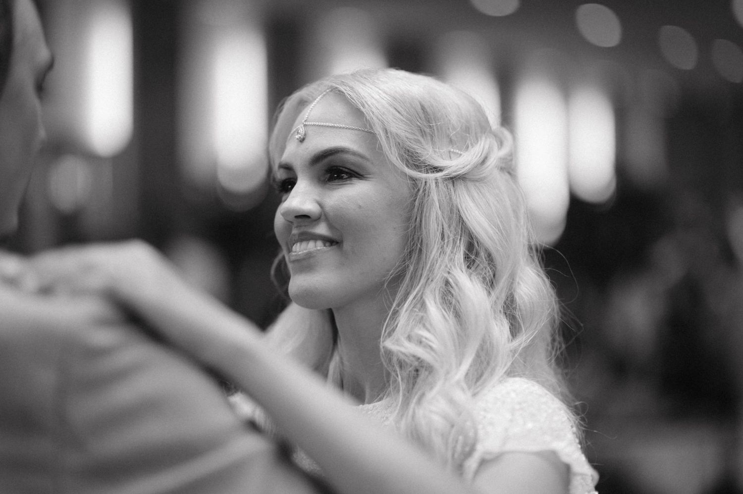 Black and white portrait of bride with elegant wavy hair smiling during wedding celebration.