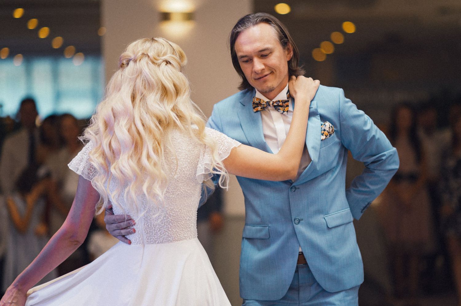 Couple in formal attire sharing intimate dance moment at indoor wedding reception.