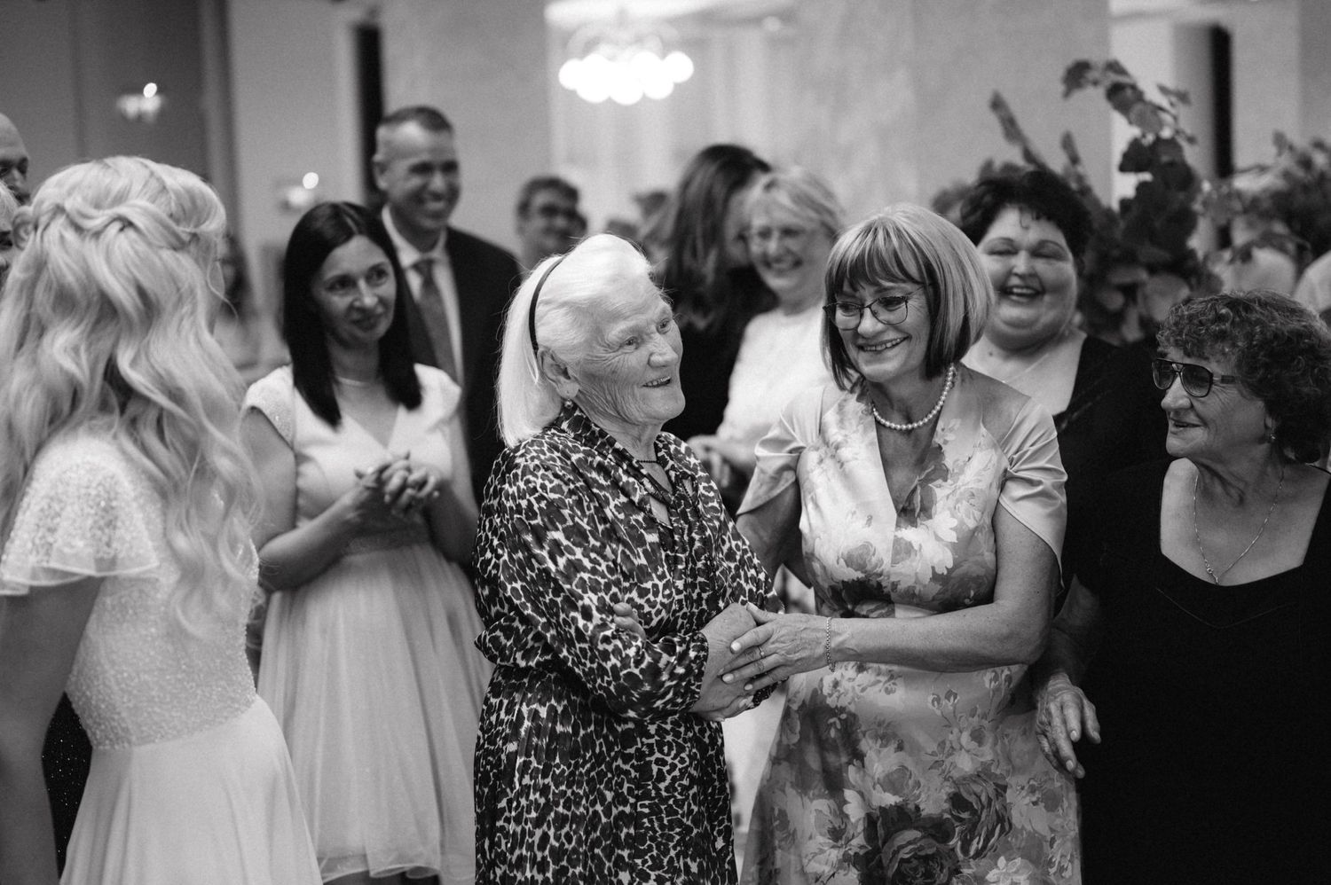 A black and white photo of guests sharing joyful moments at a celebration.