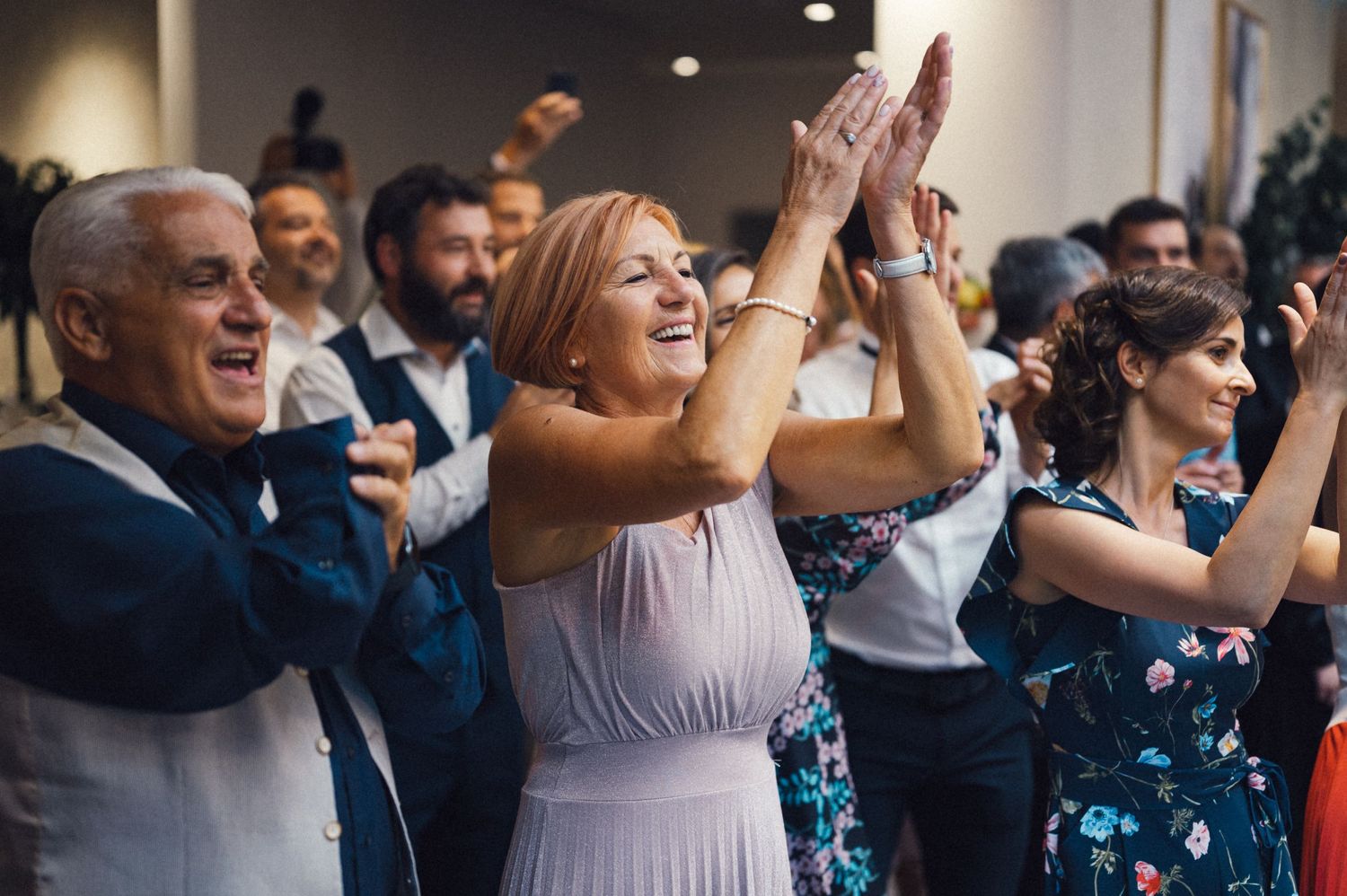 Festive wedding guests clapping and cheering during a reception celebration.