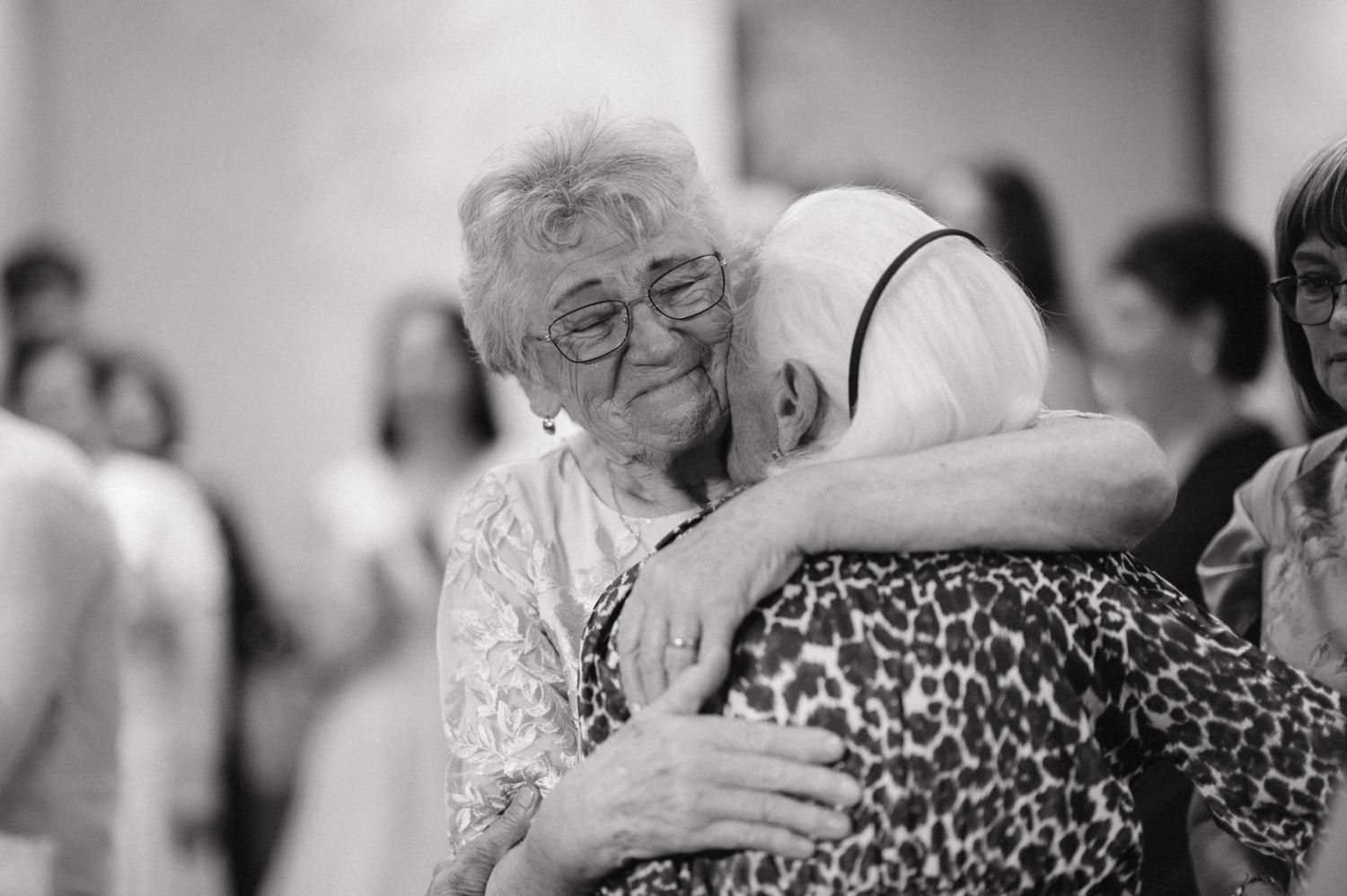 Emotional black and white moment shared between two guests at a wedding celebration.