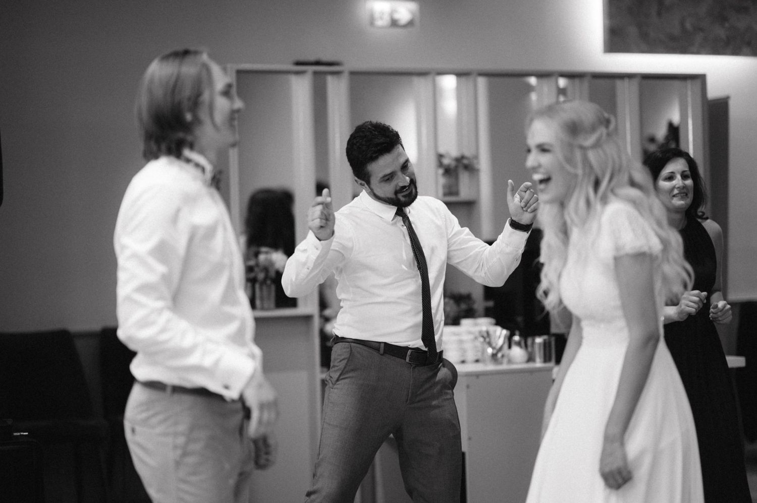 Black and white photo of guests dancing and socializing at a wedding reception.