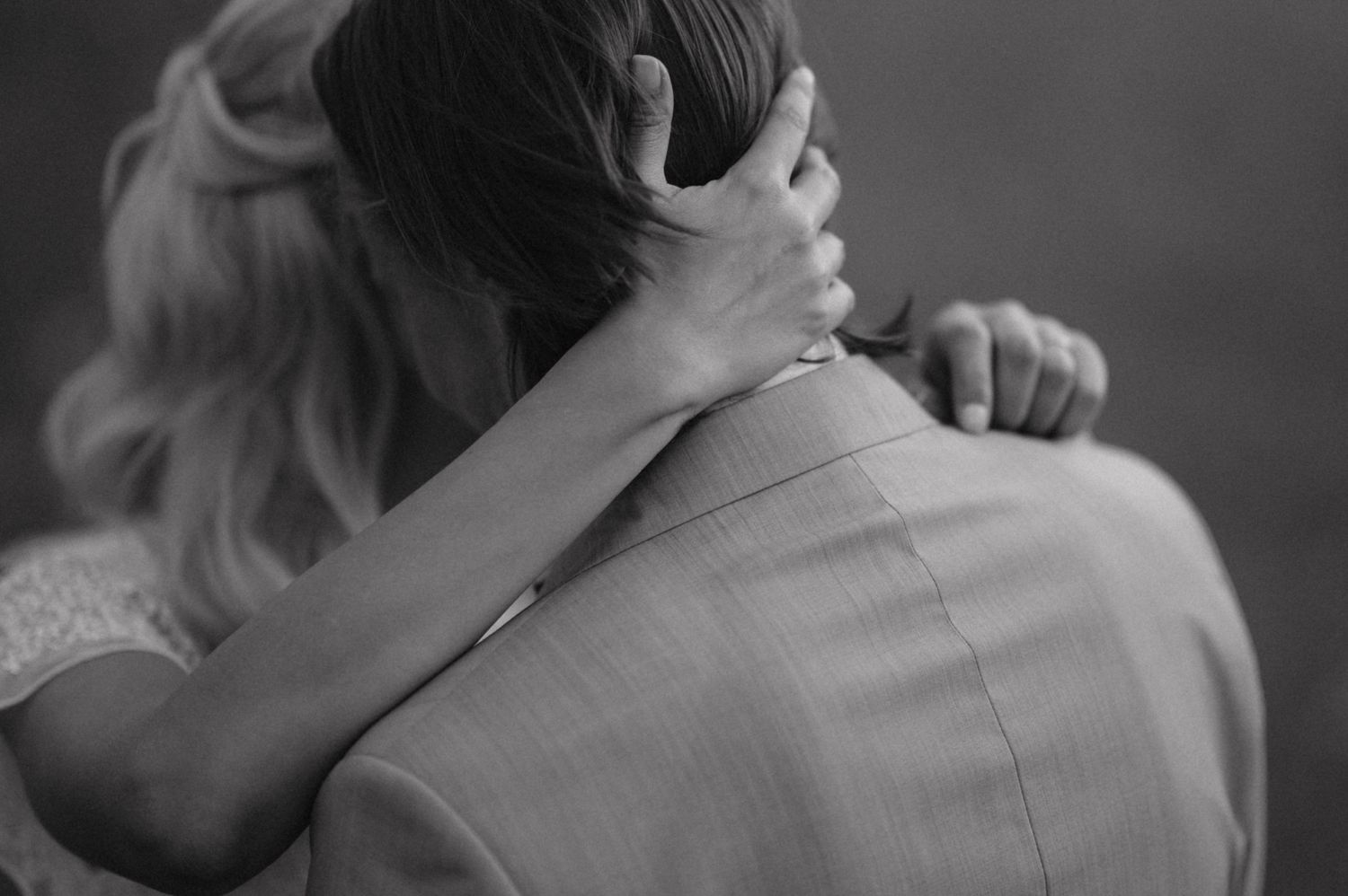 Black and white close-up of couple embracing, showing gentle touch and intimacy.