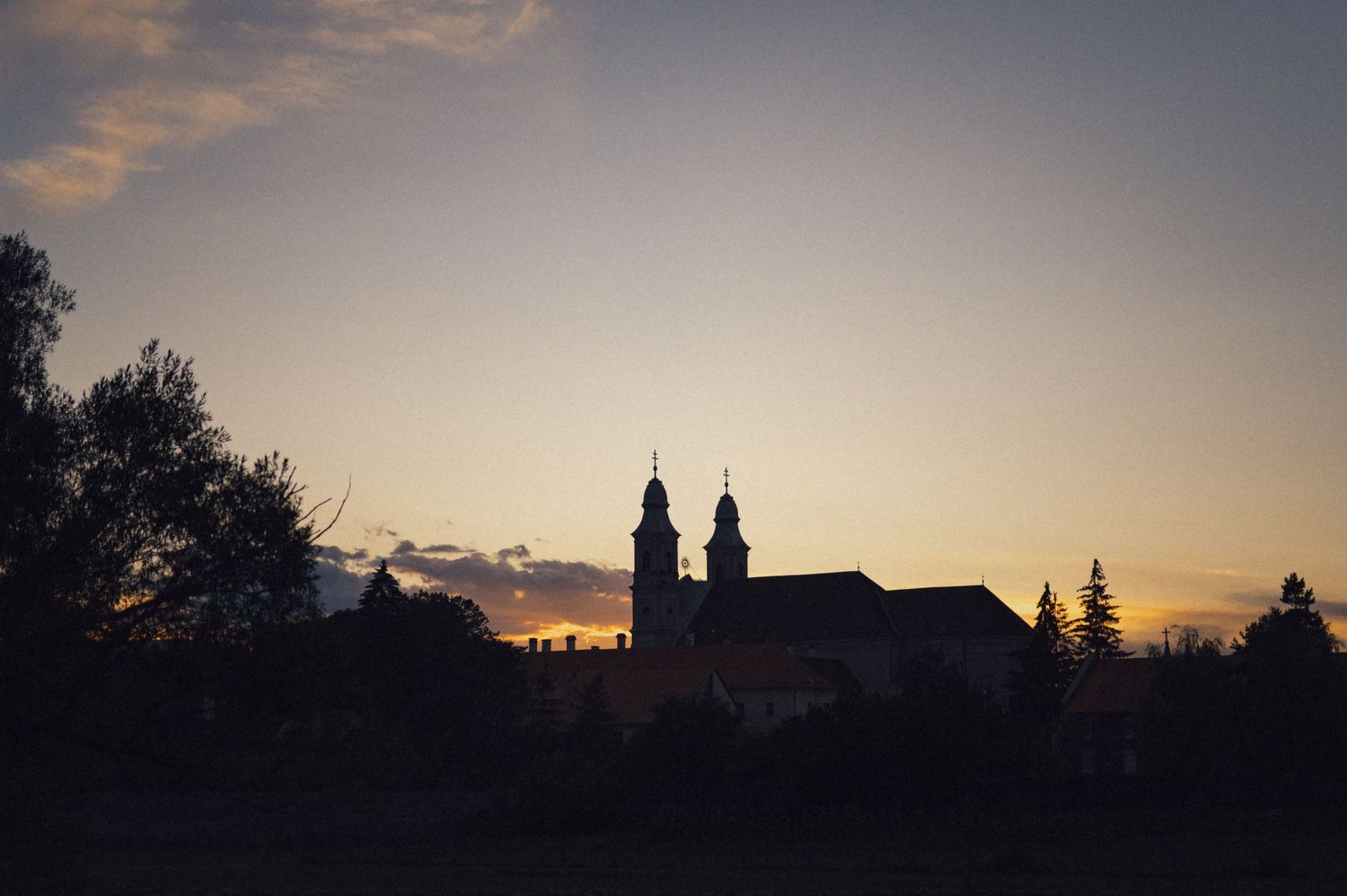 Church spires silhouetted against sunset sky.