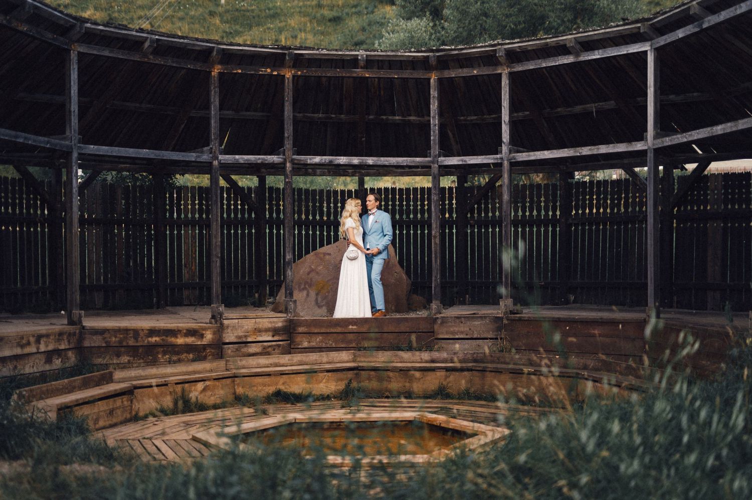 Wedding couple standing in circular stone structure with rustic architectural details.