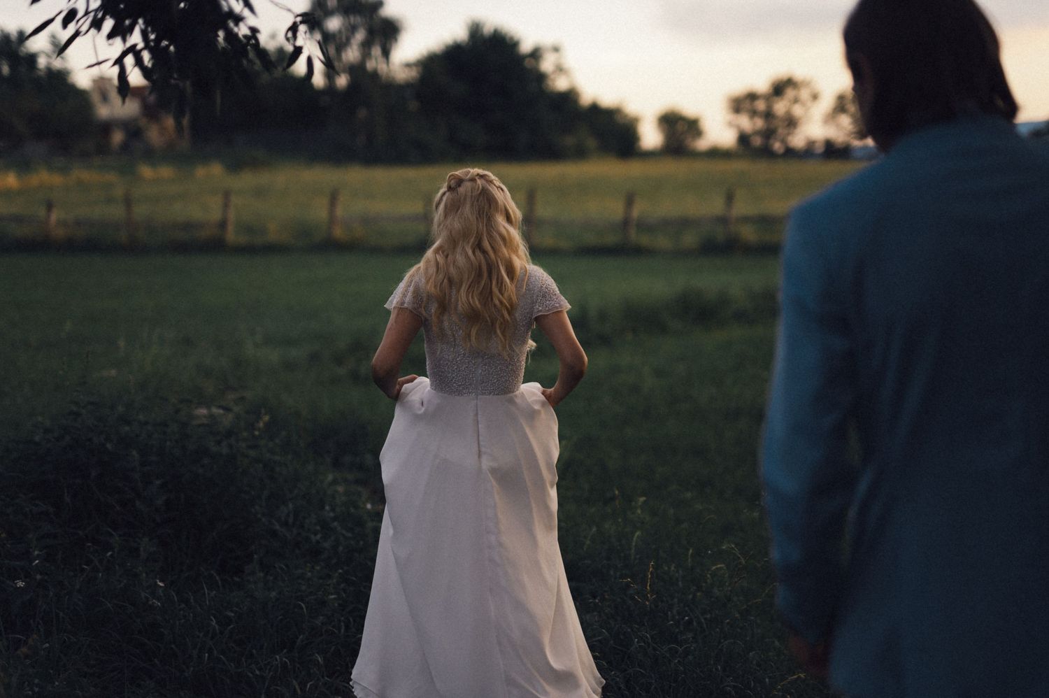 Wedding couple walking through field at dusk.