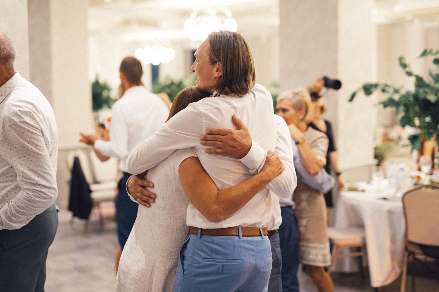 Guests sharing embraces during an emotional moment at a wedding reception.