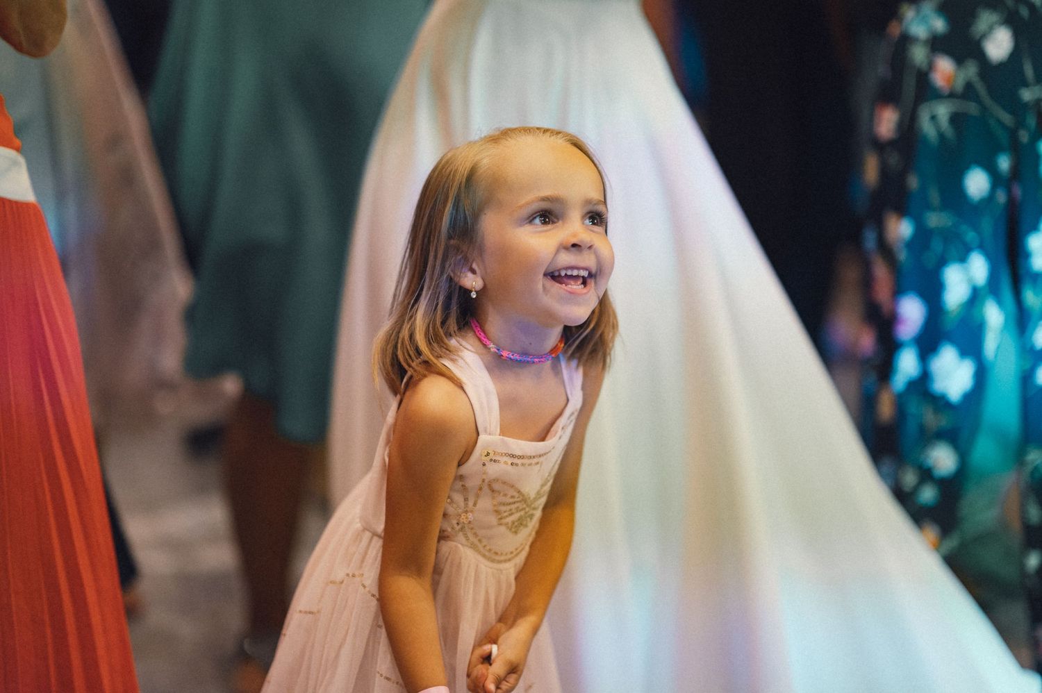 Young girl in a light dress smiles excitedly during a celebration.