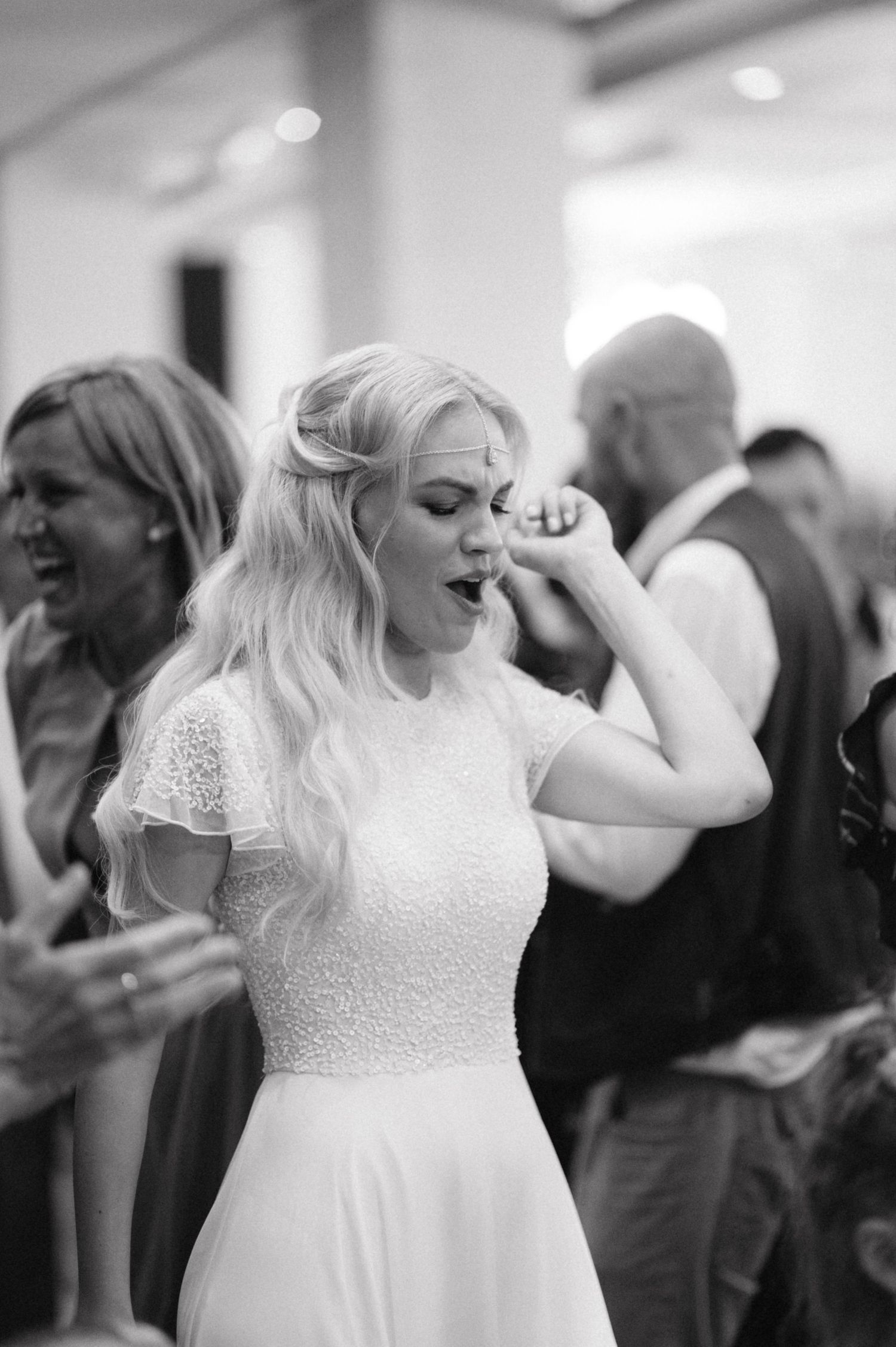 Black and white photo of a bride dancing joyfully at her wedding reception.