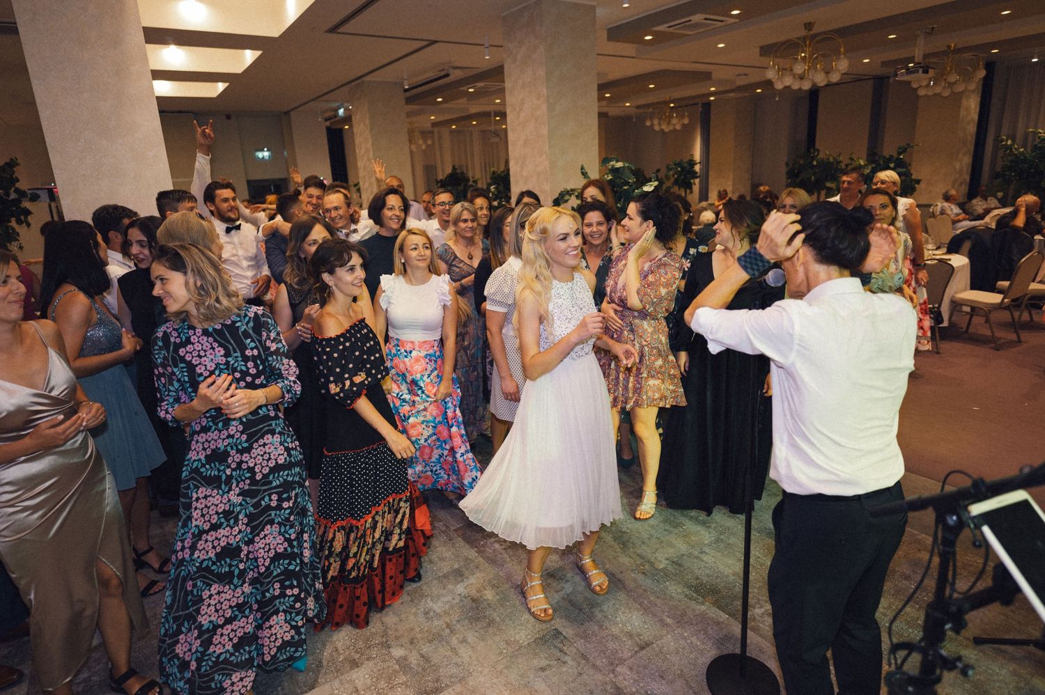 Wedding guests dancing together at a lively reception in a banquet hall.