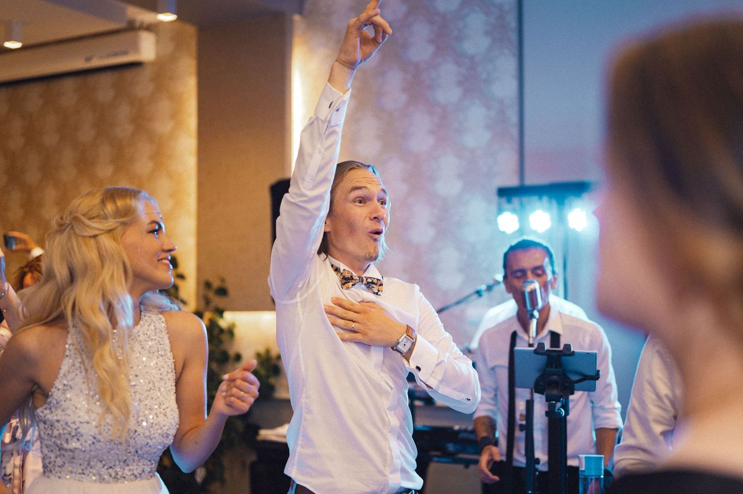 Energetic dancing and celebration at a wedding reception with festive lighting.