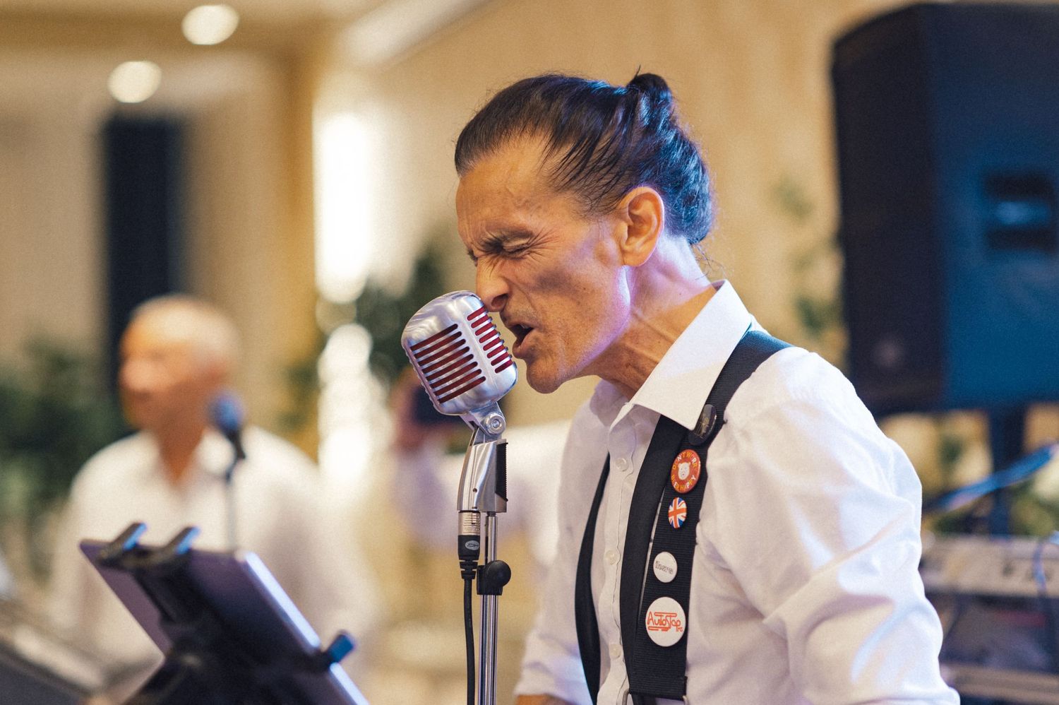 Wedding band singer performing with vintage microphone at reception.