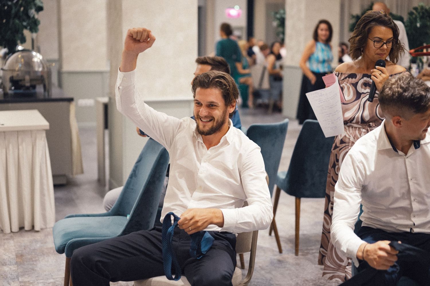 Wedding guest raises his arm enthusiastically during reception celebrations.