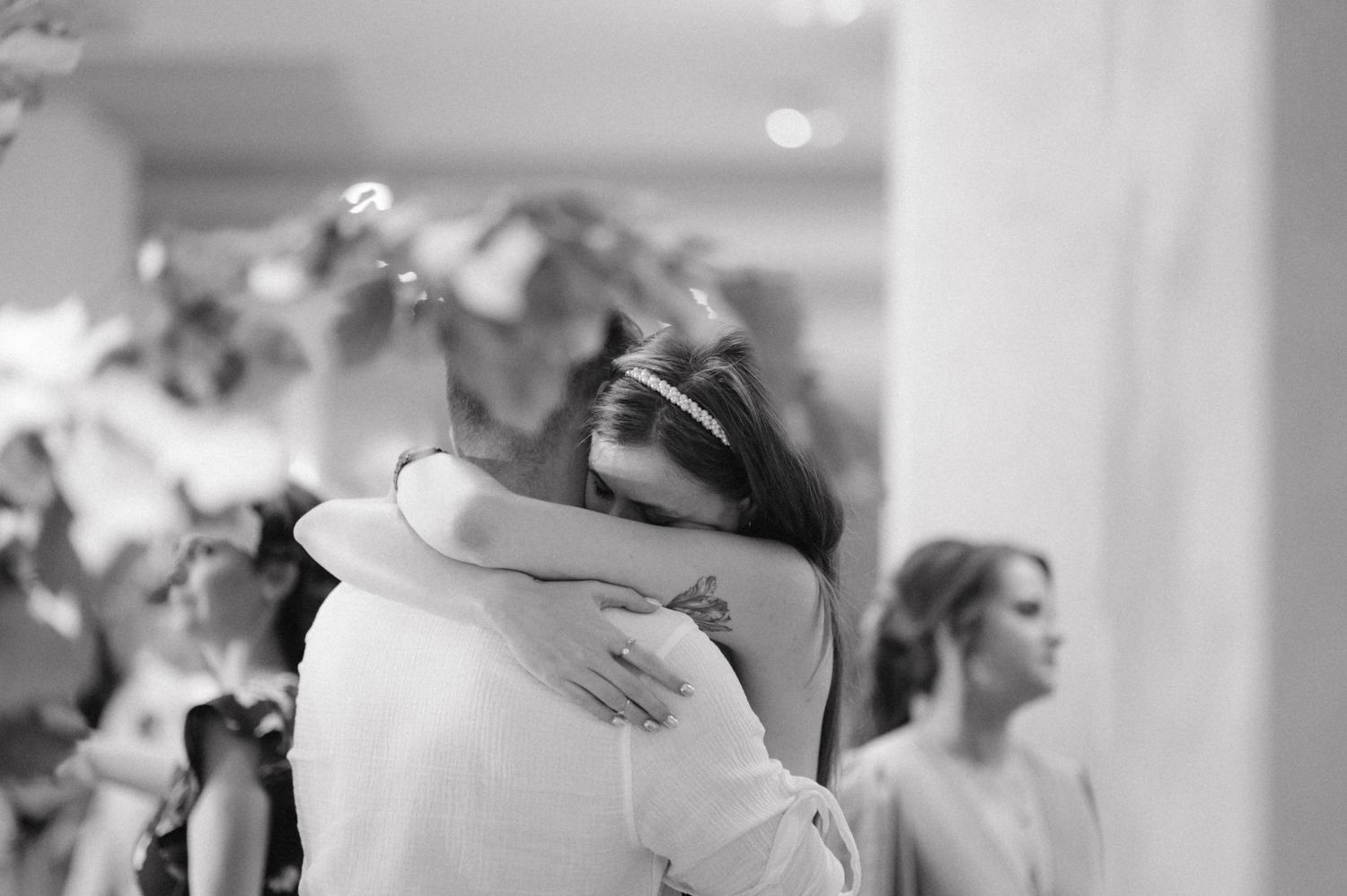 Black and white photo of two people sharing an emotional embrace at a wedding.