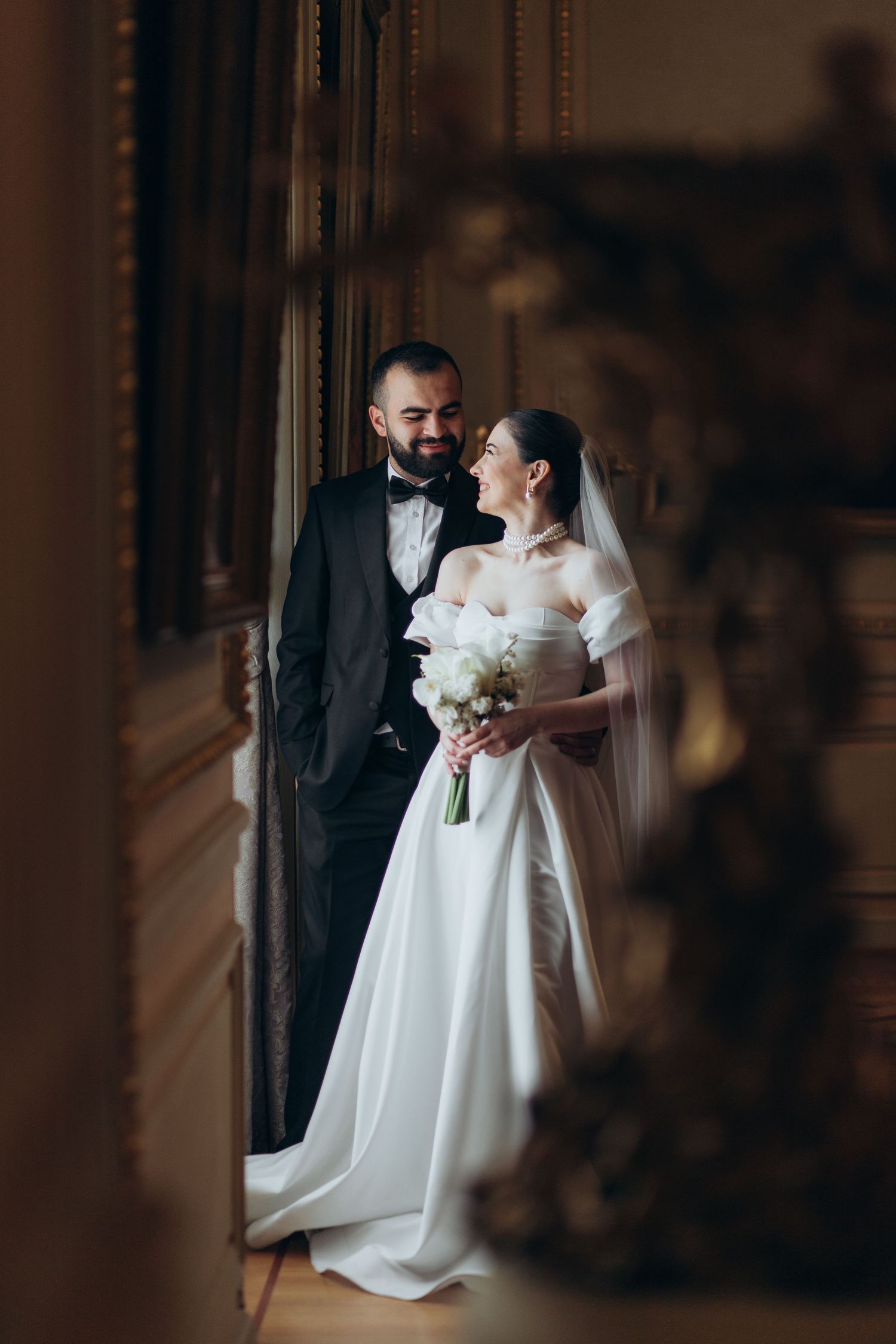 Elegant wedding portrait with couple in formal attire against a romantic vintage backdrop.