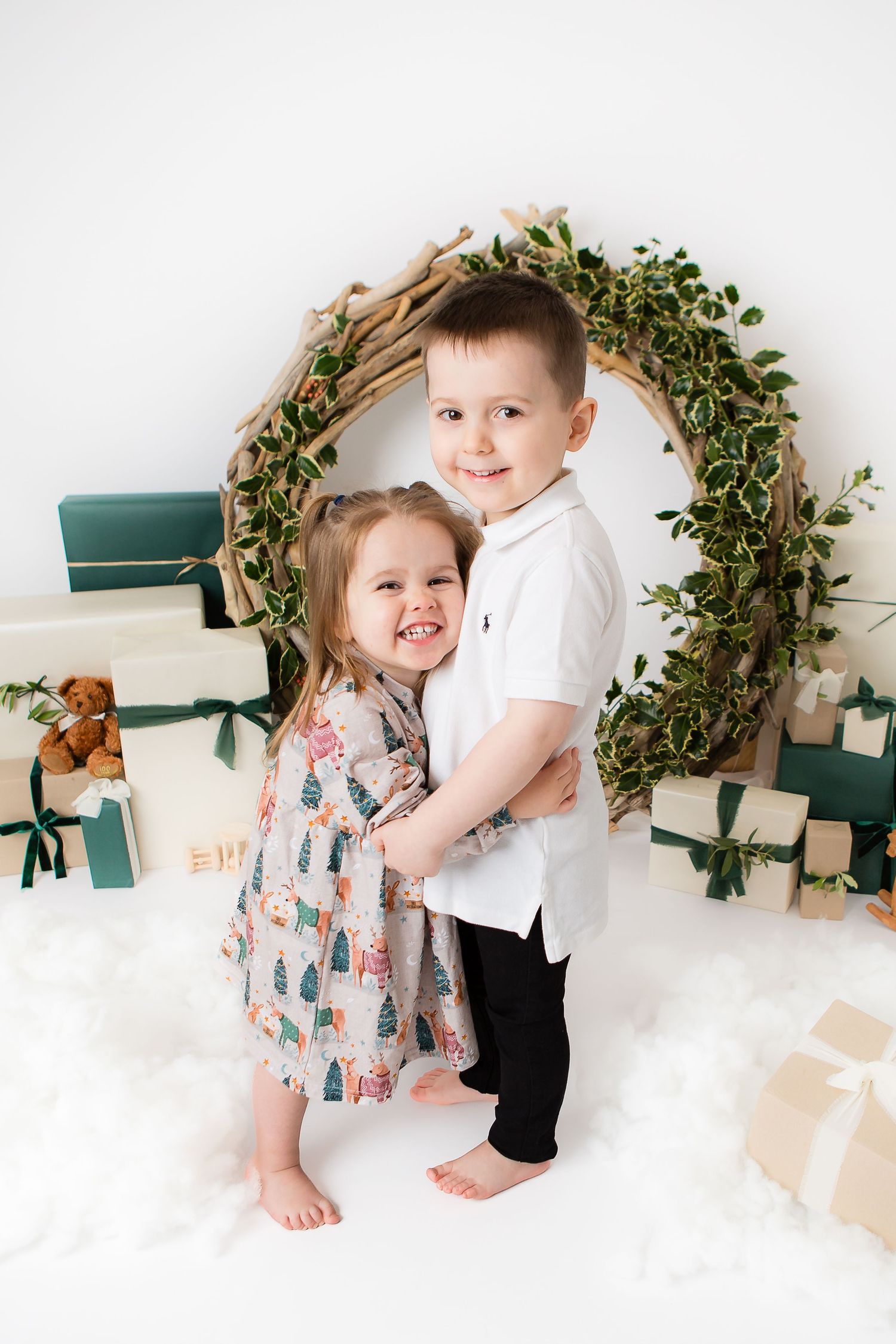 Holiday portrait setup with greenery wreath arch and wrapped presents.