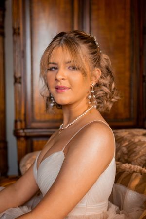 Classic bridal portrait featuring pearl jewelry against a rich wood paneled background.