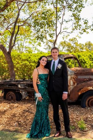 Formal couple poses in front of rustic vintage truck with green foliage background.