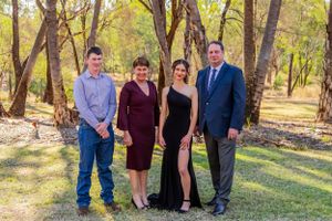 Four people pose together outdoors for a formal occasion photo.