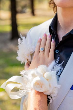 Close up of corsage and engagement ring with delicate white flowers.