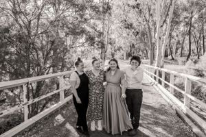 Black and white portrait of group on wooden bridge with trees in background.