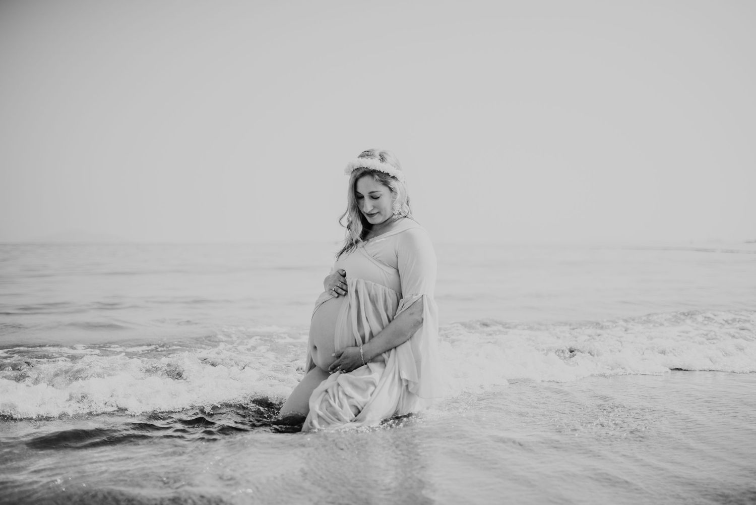 black and white photo of pregnant mother in the waves