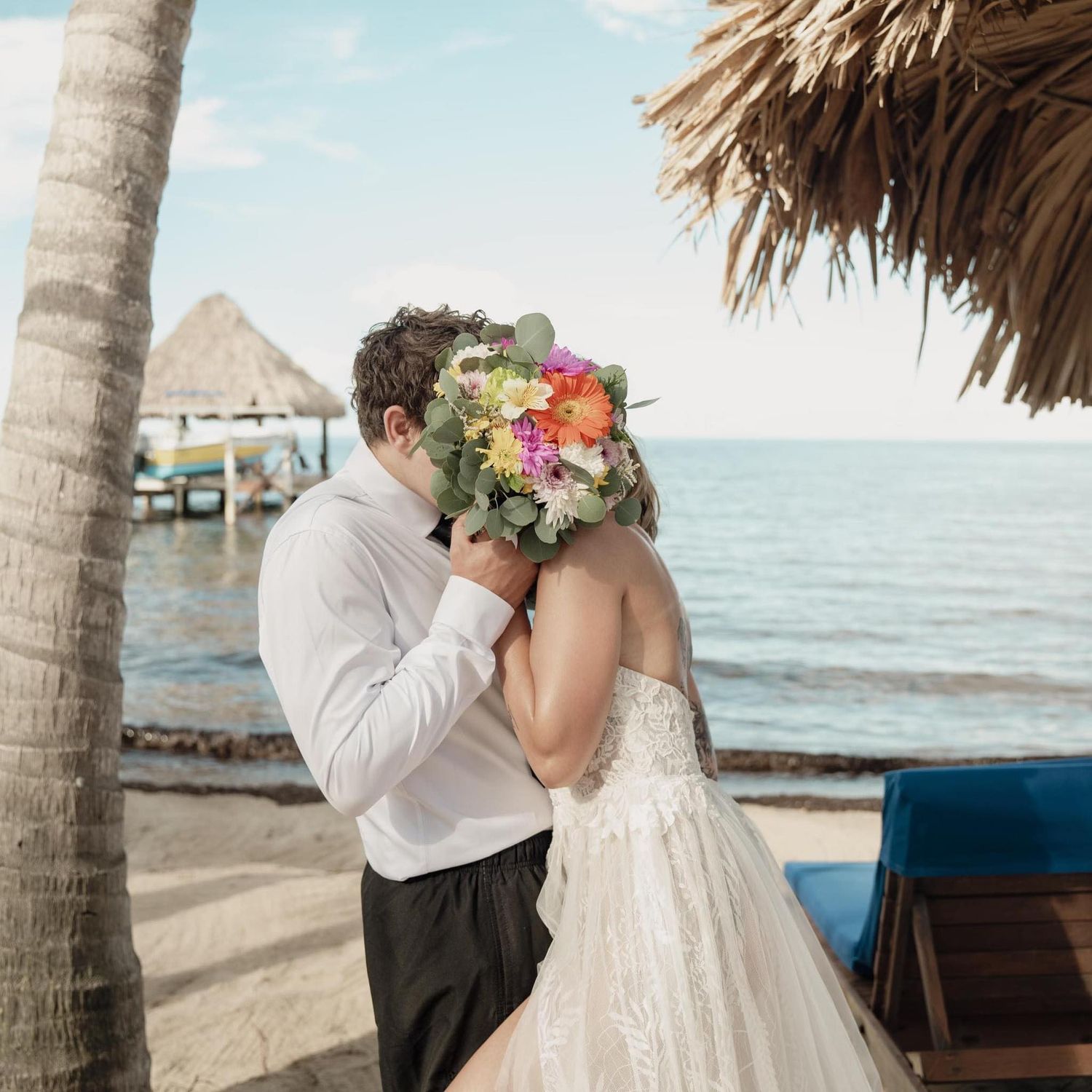 a couple kissing in their wedding photos behind a bouquet