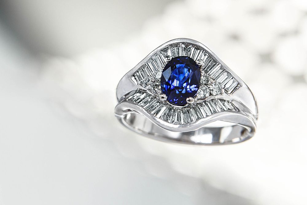 A marquise cut sapphire surrounded by baguette cut diamonds is set in a silver woman’s ring.